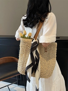 Straw tote bag with brown leather straps and scarf accessory on a model back