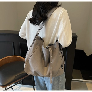 Detail of grey canvas tote bag with adjustable metal eyelet strap and side brand label