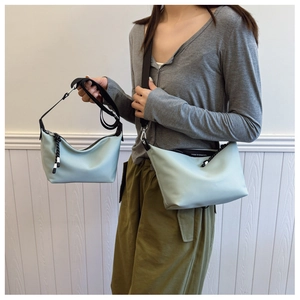 Size comparison of two light blue nylon dumpling bags with adjustable straps worn by a model