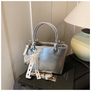 Close-up of silver pleated bucket bag with knotted handles and pearl heart charm