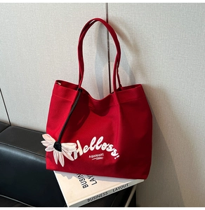 Detail of red canvas tote bag with white Hello print and cute daisy pendant ornament