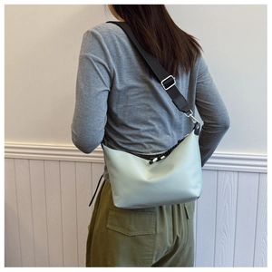 Detail of mint green crossbody bag with black strap and adjustable silver buckle