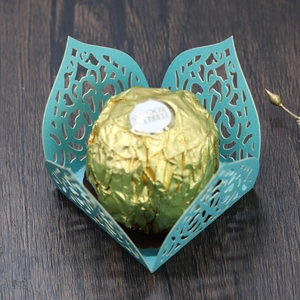 Macro detail of laser-cut turquoise paper wrap with floral vine pattern for chocolates