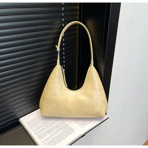 Close-up of minimalist off-white crocodile embossed hobo bag on an open book