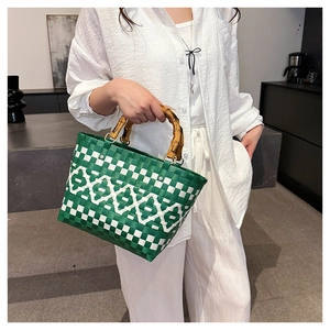 Détail du sac cabas tressé à damier vert avec poignées en bambou et anneaux dorés