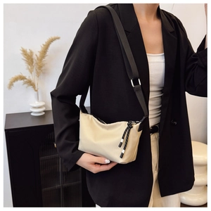 Detail of a beige crescent crossbody bag with adjustable black strap and woven cord accents