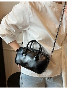 Black glossy mini bowling bag with silver ring handles and chain strap on a model