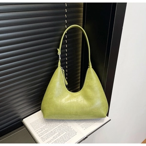 Detail of avocado green hobo bag with crocodile texture on open book prop