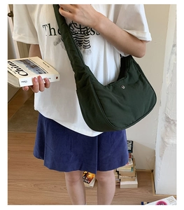 Détail d'un sac demi-lune en nylon vert foncé porté par un mannequin pour le style