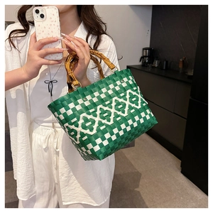 Détail du sac tissé à carreaux verts et blancs avec poignée en bambou et anneaux dorés