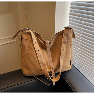 Detail of khaki canvas tote bag featuring silver metal grommets on the shoulder strap