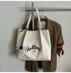 Detail of canvas tote bag featuring floral pendant and Helloss text on hanger