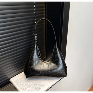 Detailed view of black crocodile pattern leather Hobo bag on minimalist book background