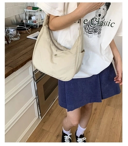 Détail du sac bandoulière croissant blanc cassé montrant la poche latérale et le logo