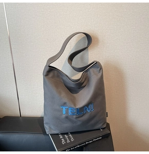 Dettaglio del ricamo blu 3D TELN! sulla borsa shopping in tela grigio scuro spessa