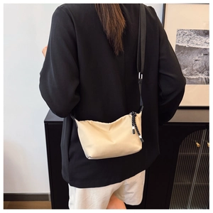 Detailed back view of a beige minimalist dumpling crossbody bag with adjustable wide strap
