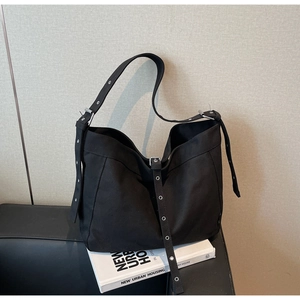Detail of black canvas tote bag showing industrial silver metal grommets and minimalist texture