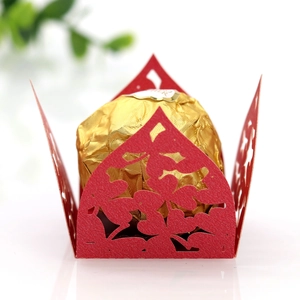 Makroaufnahme einer roten lasergeschnittenen Bonbonschachtel mit Herzmotiven und Goldkugel