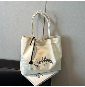 Detail of off-white canvas tote bag featuring floral pendant and Helloss typography