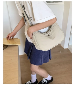 Détail d'un sac demi-lune minimaliste en nylon blanc cassé avec bouton rond vintage