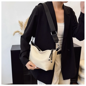 Detail of beige dumpling bag with soft leather texture and wide nylon shoulder strap
