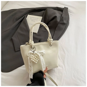 Detail of cream white bucket bag with retro wrinkled texture and pearl heart charm