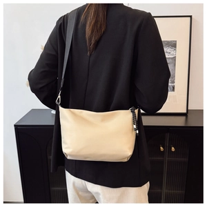 Detail of cream crossbody bag with black nylon strap and striped zipper rope detail