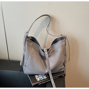Detail view of a large grey canvas tote bag with adjustable shoulder strap and silver buckle