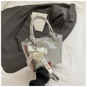 Silver metallic tote bag detail with white lace bow and pearl heart charm accessory