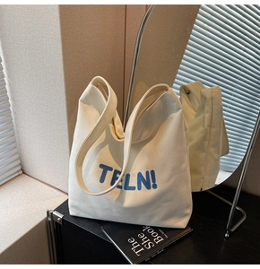 Dettaglio borsa tote minimalista in tela crema con ricamo blu TFLN! e manici spessi