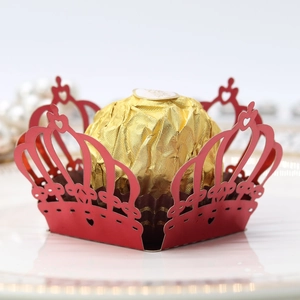 Detail of red laser-cut crown chocolate wrapper with a golden foil truffle on a porcelain plate