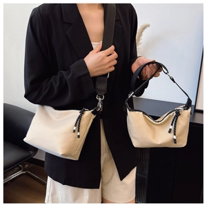 Detail shot of beige dumpling bags in two sizes with adjustable black nylon straps