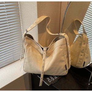 Detail of canvas shoulder bag with adjustable strap featuring silver metal eyelets
