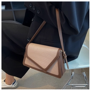 Detail of a contrast color beige crossbody bag with faux crocodile pattern and V-flap