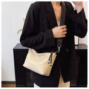 Detail of beige shoulder bag with black wide strap and silver metal buckle hardware