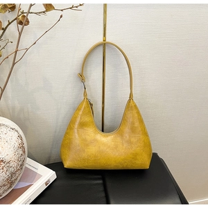 Detail of yellow crescent shoulder bag with crocodile embossed leather texture