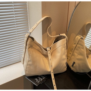 Detail view of adjustable wide canvas shoulder strap with metal eyelets on beige hobo bag