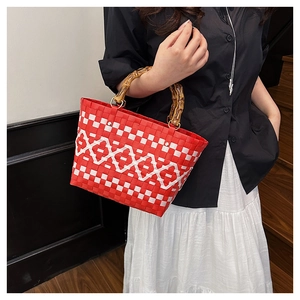 Détail du sac seau tressé rouge et blanc avec poignées en bambou et motifs en losanges