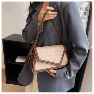 Detail of color-block underarm bag with crocodile texture and V-shaped flap on model