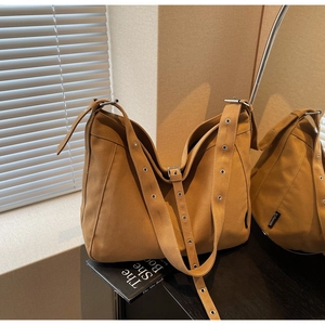 Detail of adjustable metal buckle strap and logo label on caramel canvas tote bag