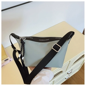 Detail of light green dumpling bag showing brand lettering and woven zipper puller