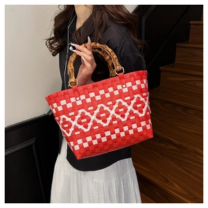 Détail du sac seau tressé rouge et blanc avec des poignées en bambou naturel