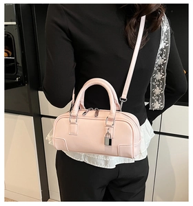 Detail of pink mini Boston bag with silver hardware worn over the shoulder by a model