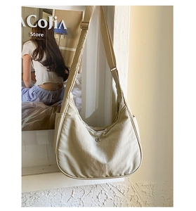 Détail du sac hobo beige avec bandoulière réglable et logo métallique rond
