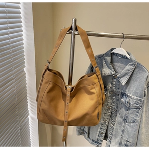 Detail of canvas hobo bag with metal eyelets and wide shoulder strap in mustard yellow
