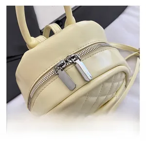 Détail des fermetures à glissière en métal argenté sur ce sac à dos matelassé couleur crème