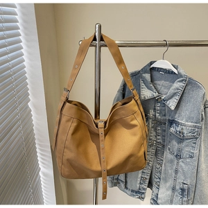Detail of vintage canvas hobo bag with wide grommet strap and vertical buckle accent