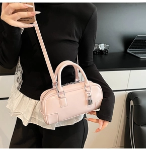 Detail of light pink Boston handbag with silver hardware and decorative metal padlock