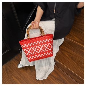 Détail du sac tissé à carreaux rouges et blancs avec une poignée en bambou naturel