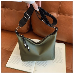 Detail of olive green nylon bag with woven strap and rope zipper pull on sofa
